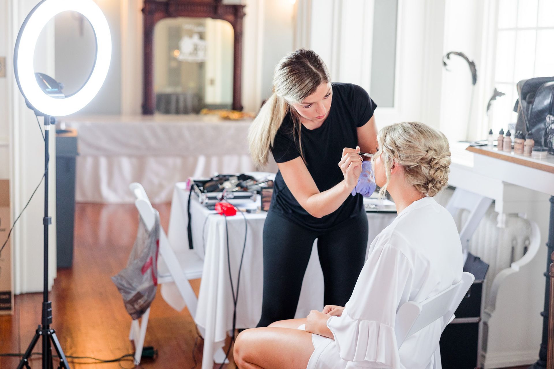 A woman is getting her makeup done by a makeup artist in a room.