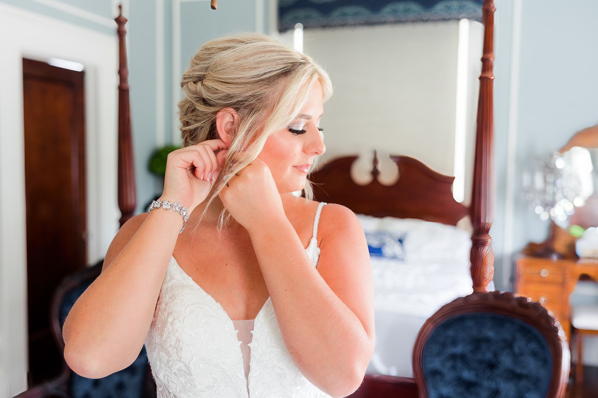 A woman in a wedding dress is putting on her earrings.