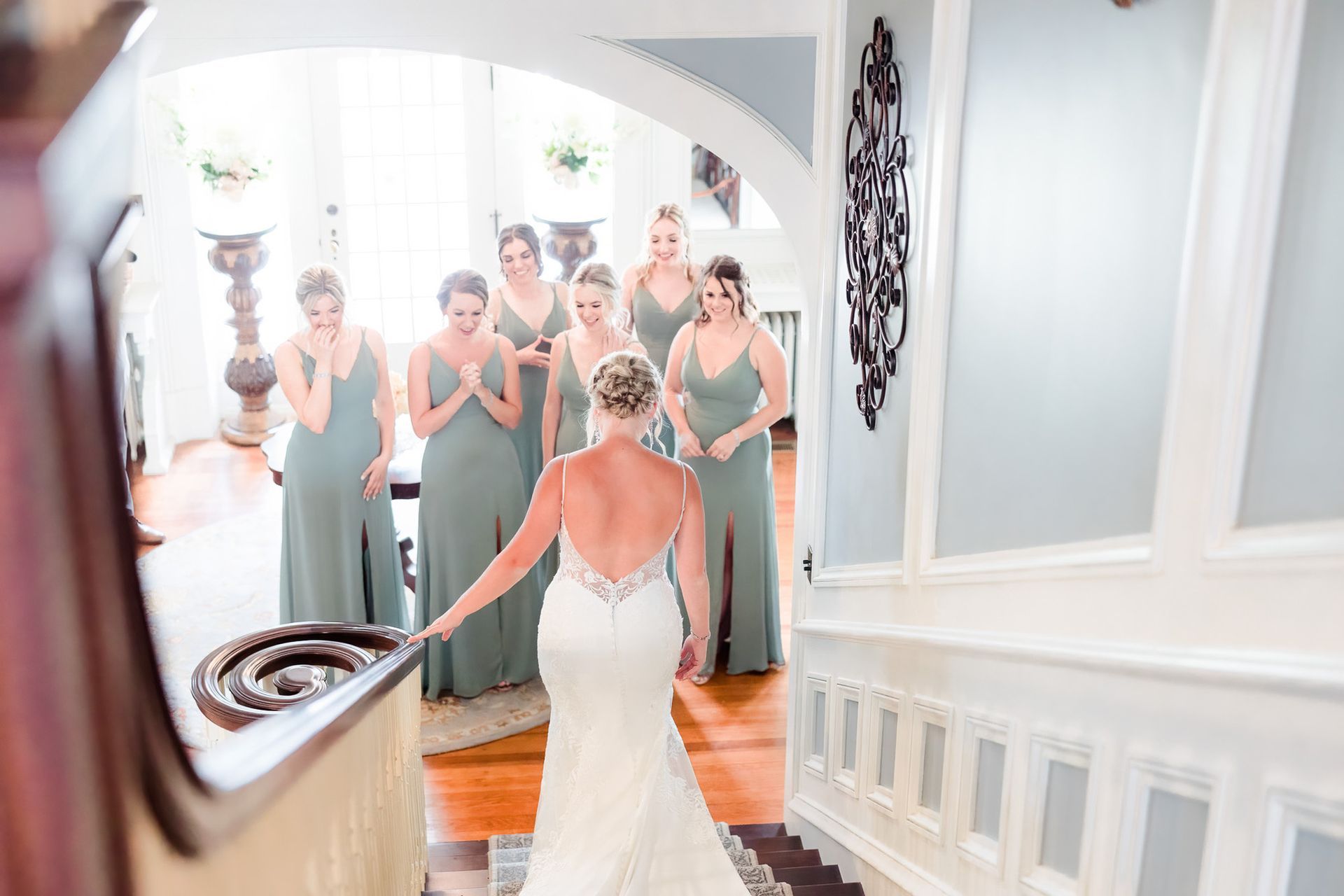 A bride and her bridesmaids are standing in front of a mirror.