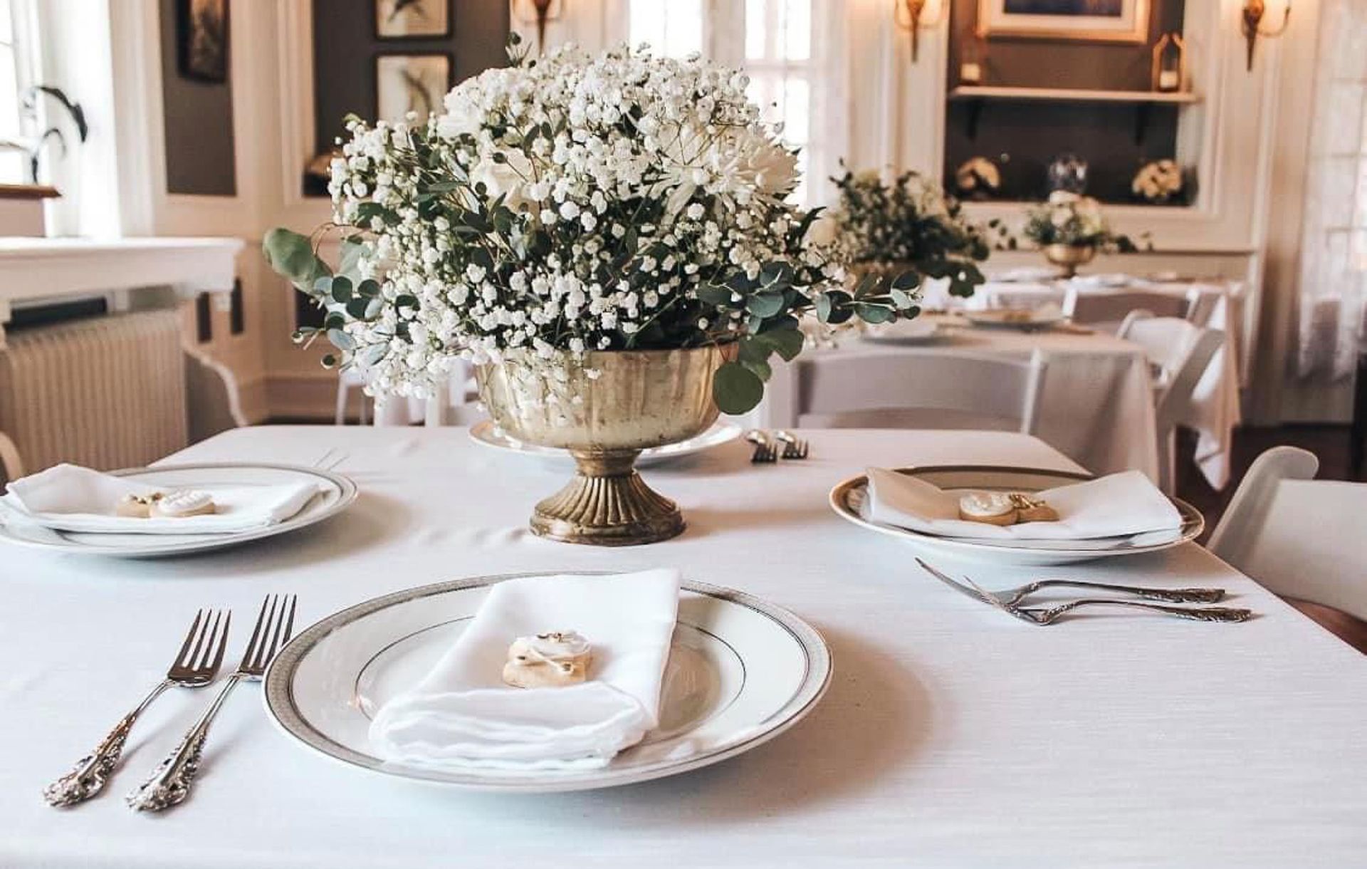 A table with plates , silverware , and a vase of flowers on it.