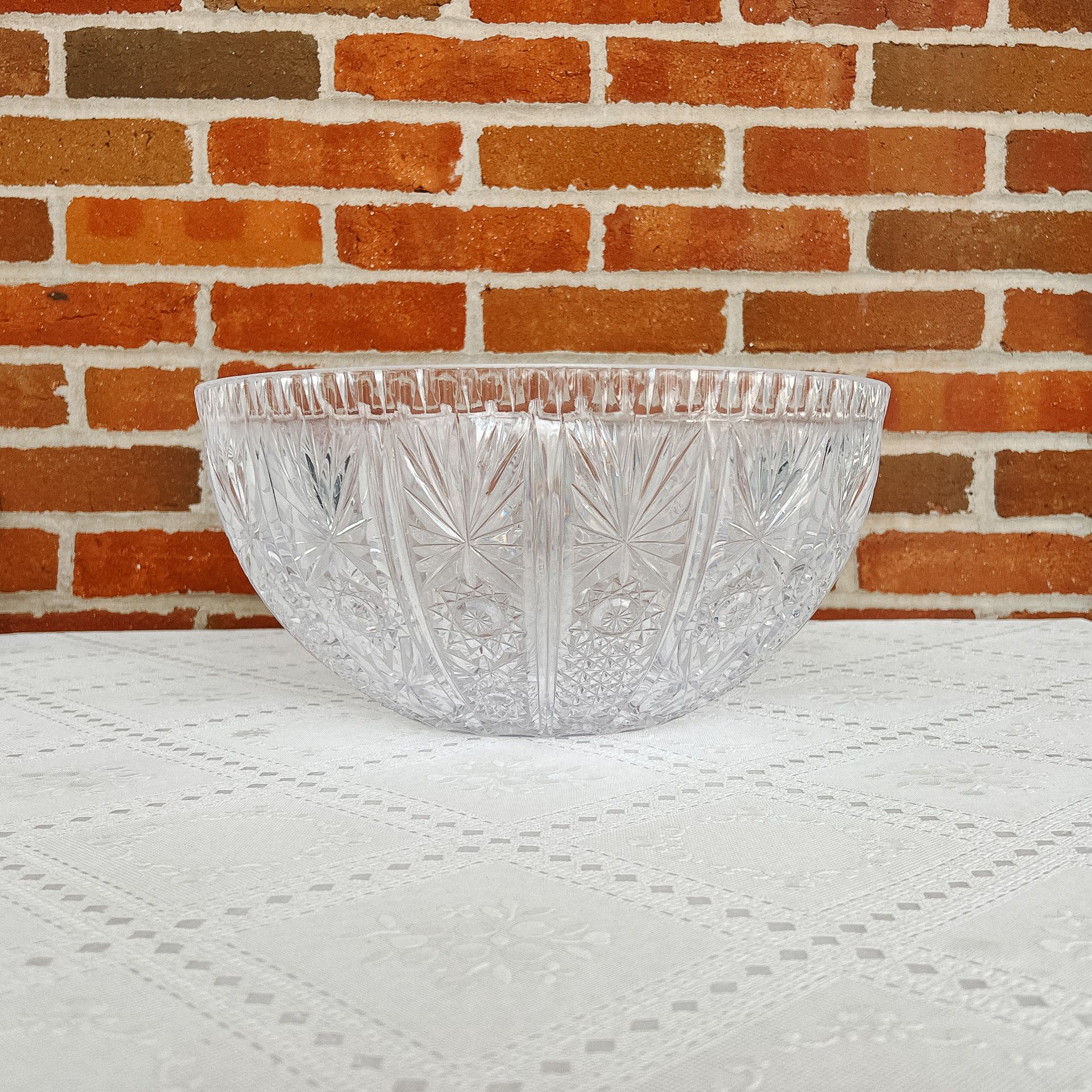 A clear glass bowl is sitting on a table in front of a brick wall