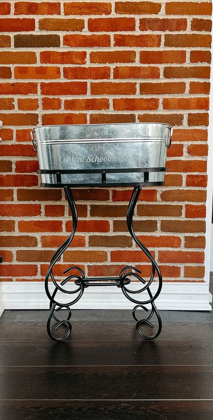 A metal planter is sitting in front of a brick wall.