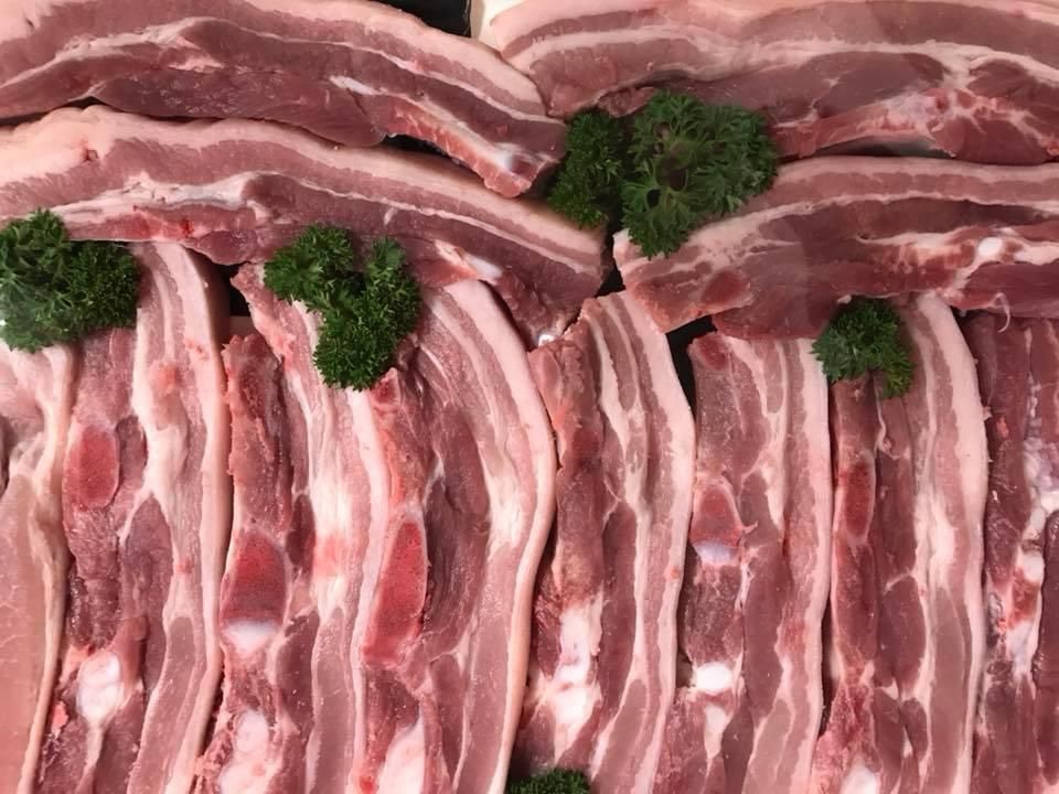 A Close up Of a Pile of Raw Pork Ribs with Parsley on Top — Holiday Coast Meat & Smallgoods in South Grafton, NSW
