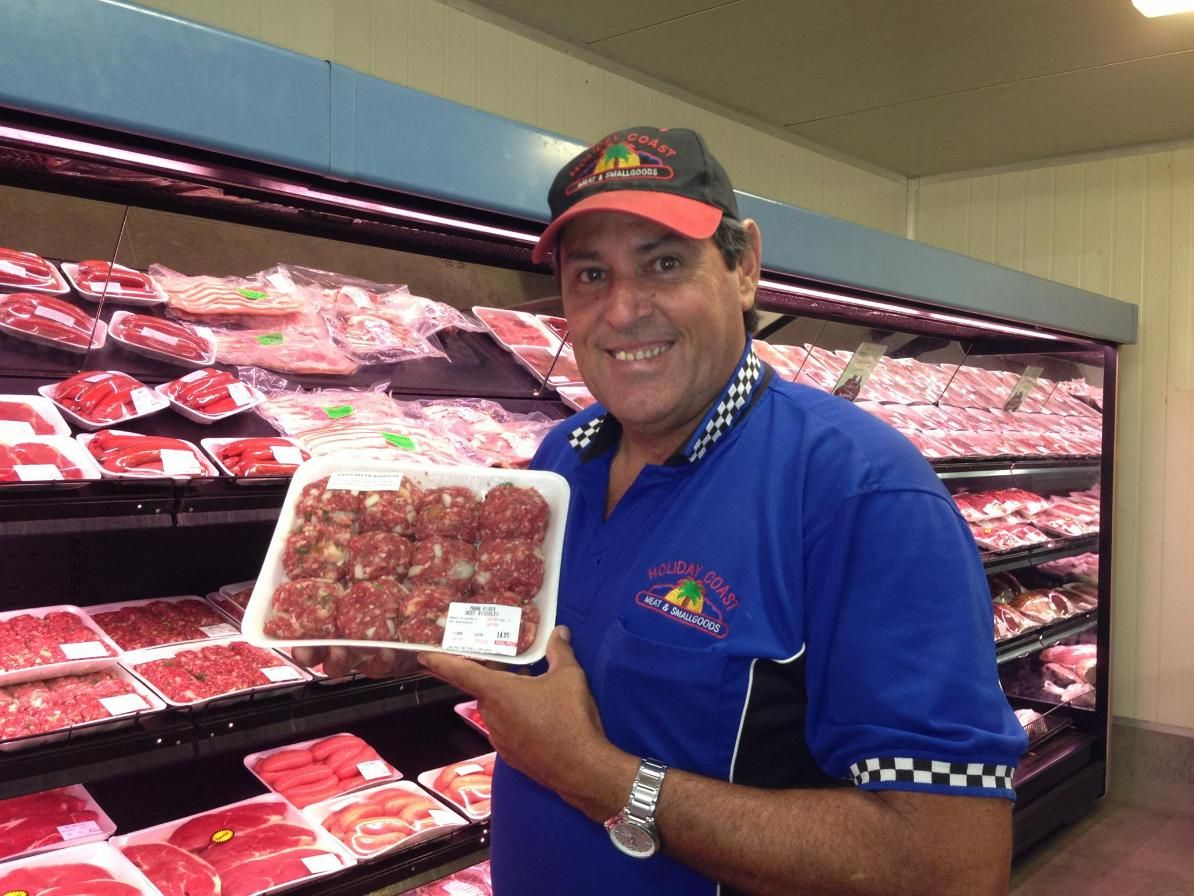 A Man in A Blue Shirt Is Holding a Tray of Meat — Holiday Coast Meat & Smallgoods in South Grafton, NSW
