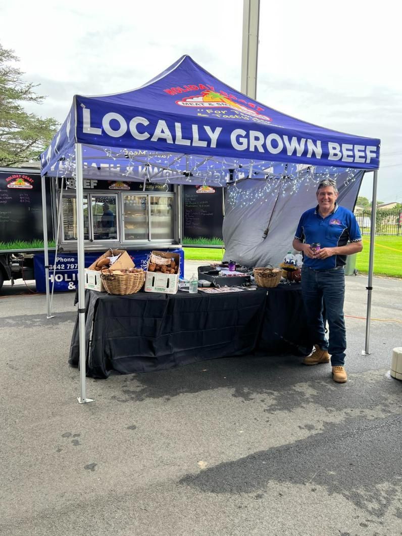 A Man Is Standing in Front of A Tent that Says Locally Grown Beef — Holiday Coast Meat & Smallgoods in South Grafton, NSW