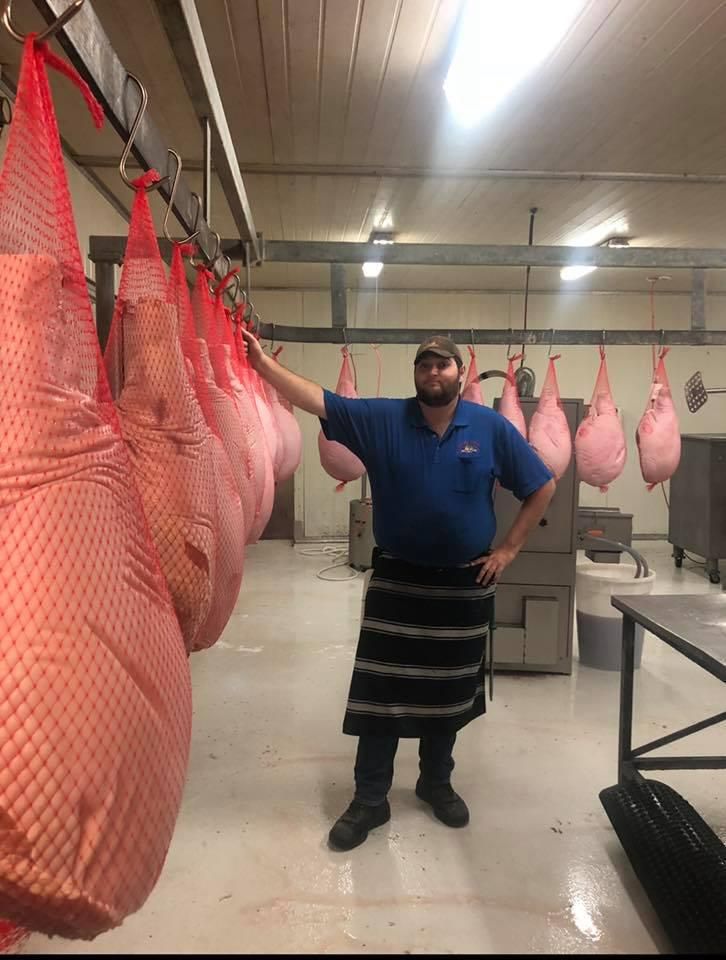 A Man Is Standing in A Room with Bags of Meat Hanging from The Ceiling — Holiday Coast Meat & Smallgoods in Grafton, NSW