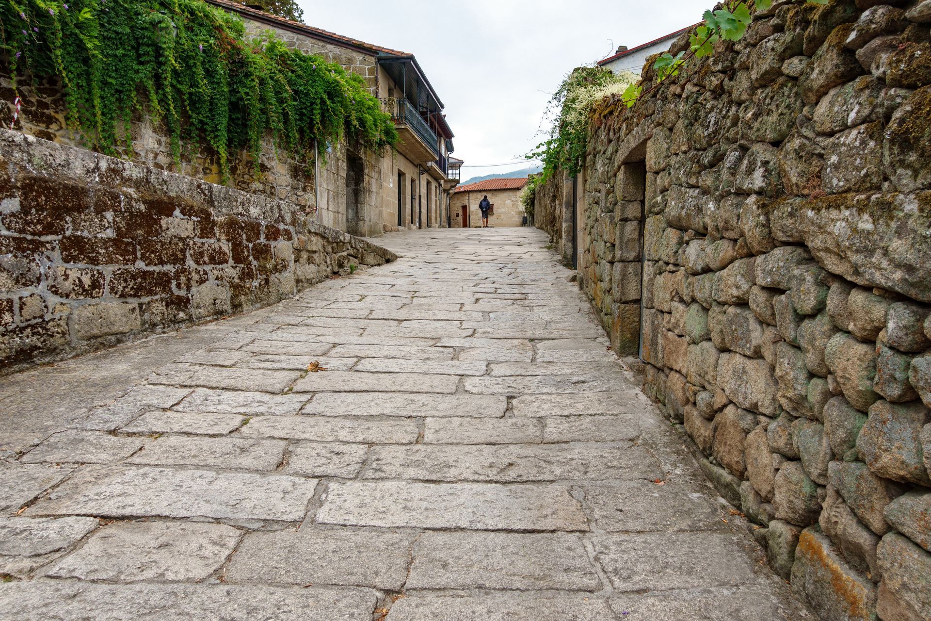 Una strada acciottolata tra due muri di pietra in un villaggio.