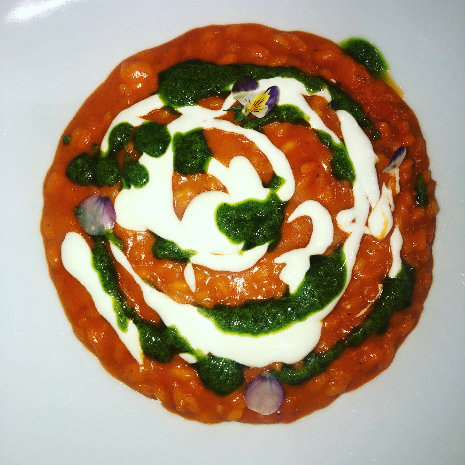 Vista dall'alto di una pizza condita con salsa, volute di formaggio bianco, erbe aromatiche e pezzetti di cipolla.