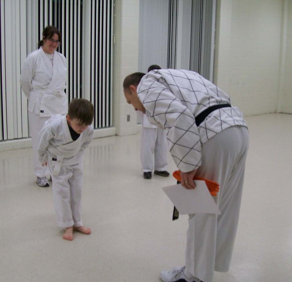 A man in a karate uniform holds a piece of paper