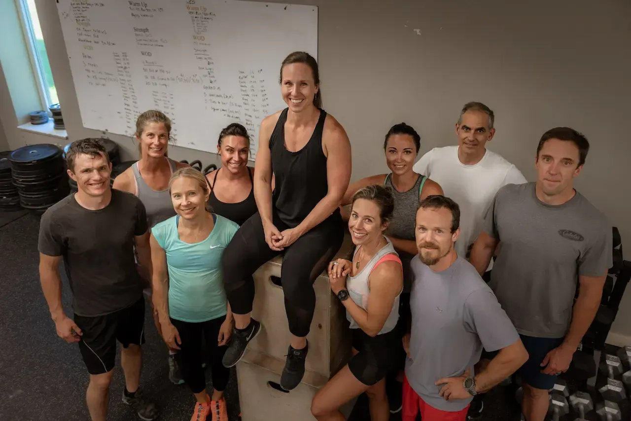Group of people in workout attire posing for a photo in a gym.