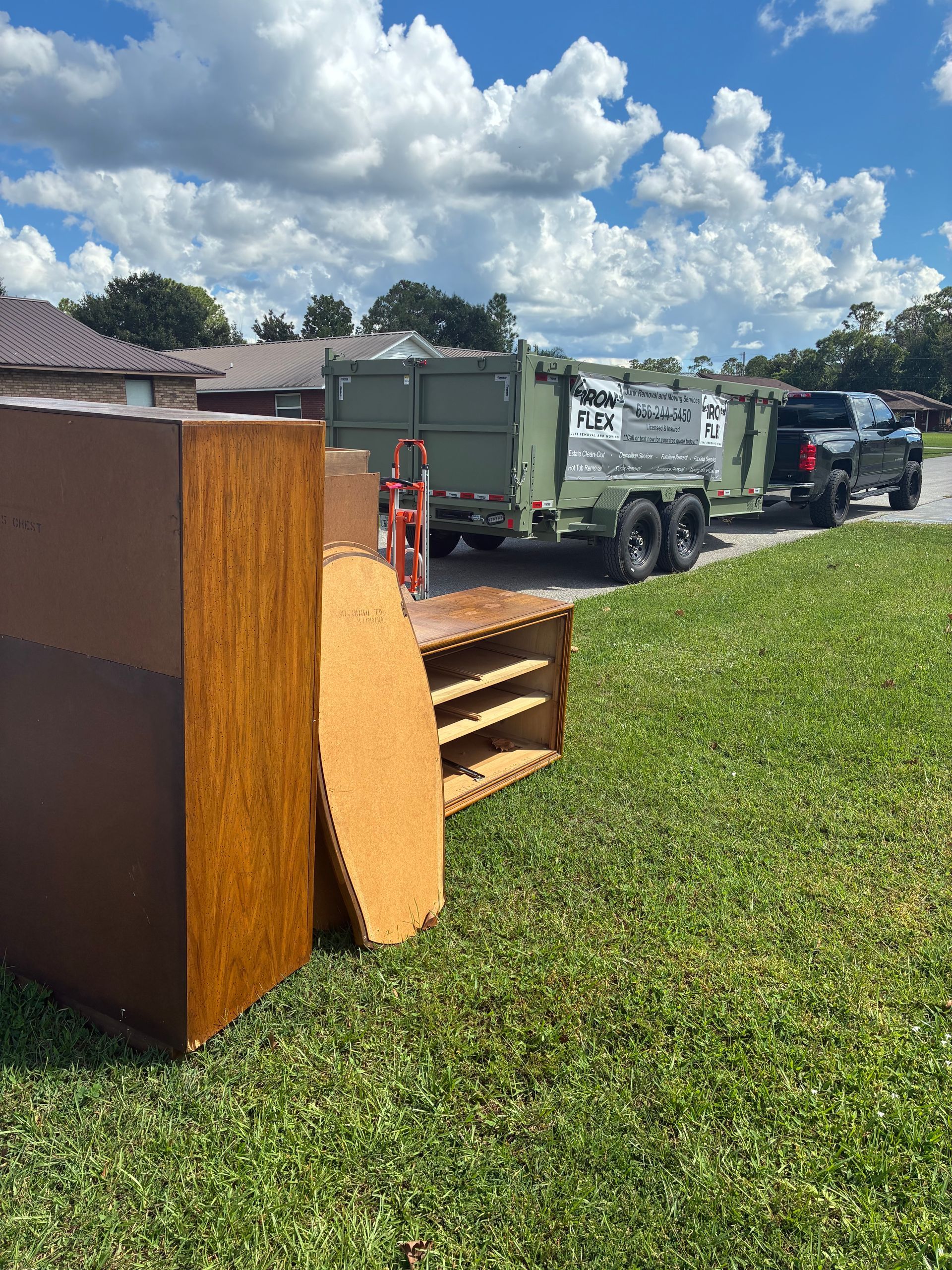 Furniture piled on lawn; truck with trailer ready for pickup, residential street.