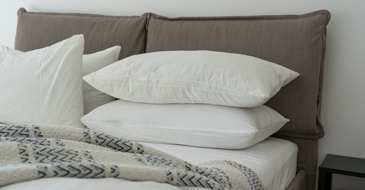 Bed with white pillows, a patterned blanket, and a brown headboard.