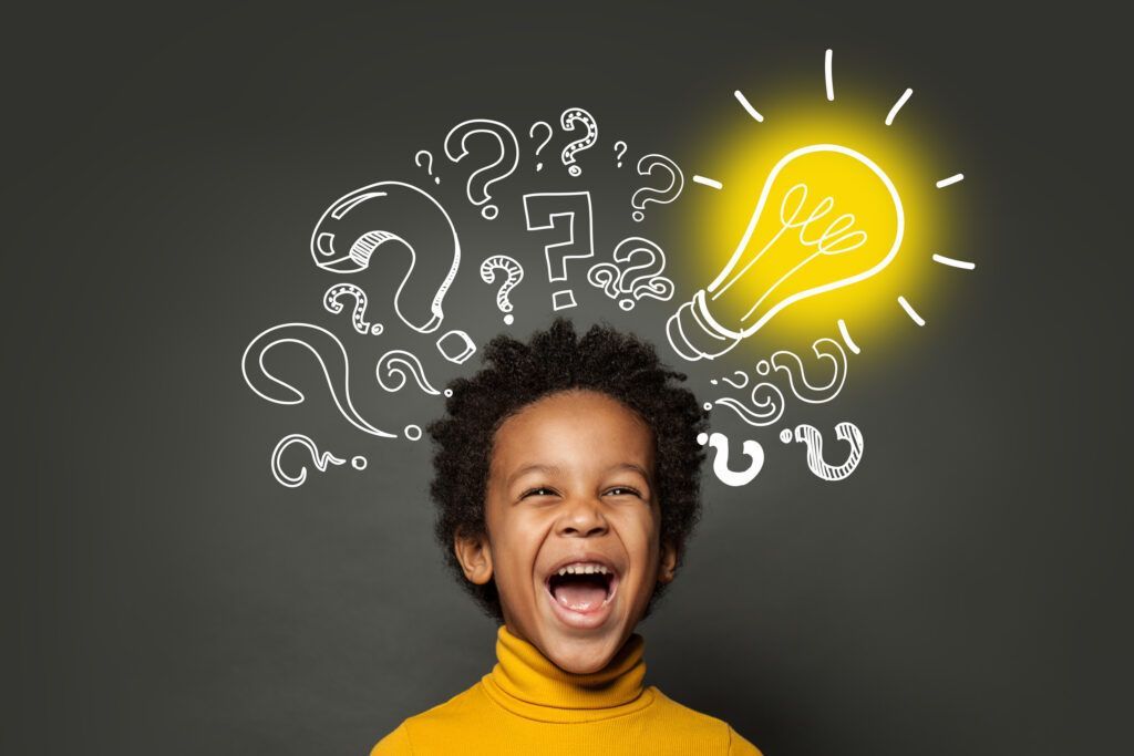 Smiling child in yellow sweater with sketched question marks and glowing light bulb above head