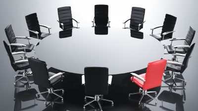 Circle of black office chairs with one red chair on a glossy floor