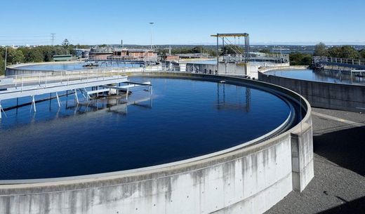 Water treatment plant with large circular settling tanks and blue water under a clear sky