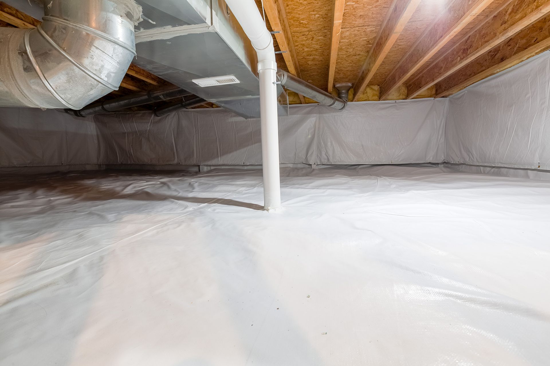 A basement with a lot of white plastic on the floor.