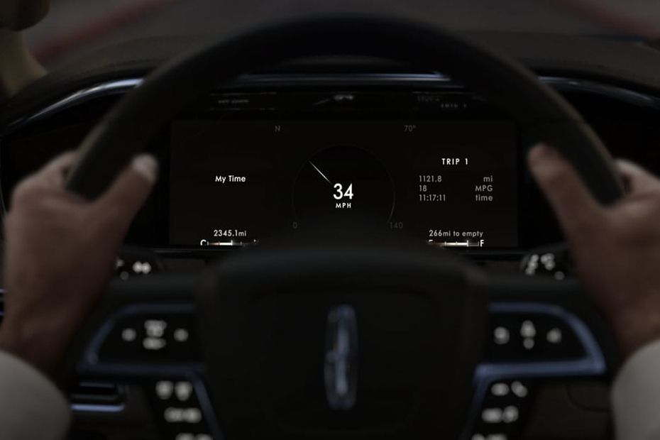 Driver’s view of a car dashboard showing 34 mph on a digital display, hands on the steering wheel