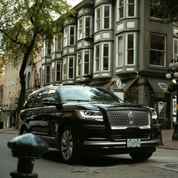 Black SUV parked on a cobblestone street beside historic buildings and street lamps.