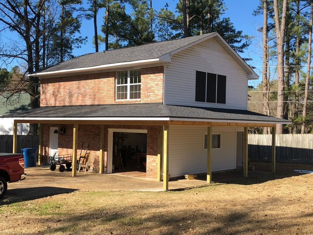 A two-story building with brick on the left and white siding on the right, featuring a large covered patio and garage.