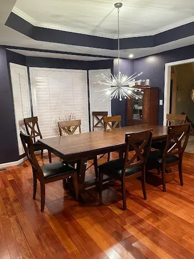 Dining room with a wooden table and chairs, hardwood floors, and a modern chandelier.