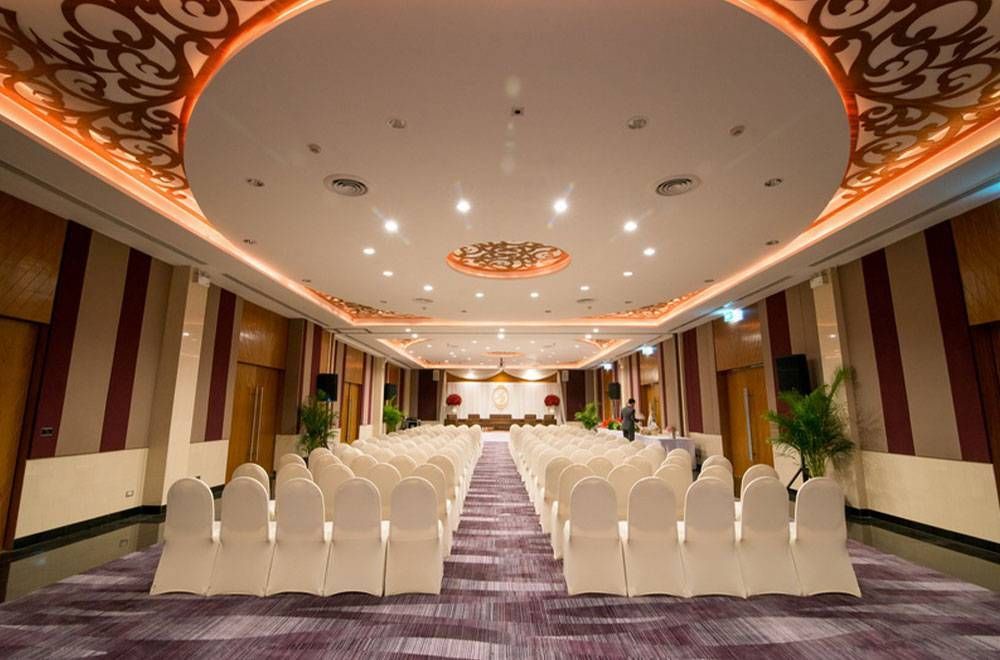 ห้องจัดงานอย่างเป็นทางการตกแต่งอย่างสวยงามด้วยเก้าอี้สีขาวเรียงเป็นแถวหันหน้าเข้าหาเวที เพดานประดับประดาอย่างวิจิตร และพรมปูพื้นลวดลาย