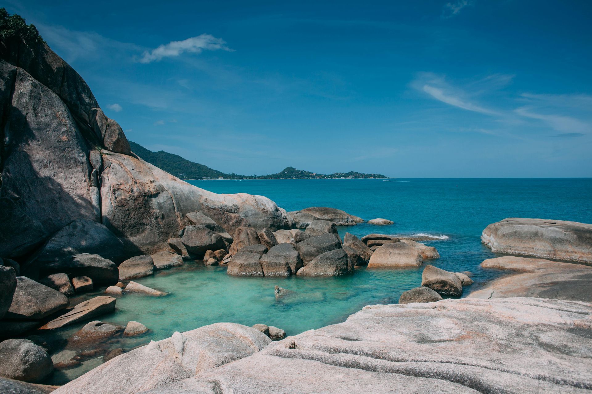 ชายหาดหินที่มีน้ำทะเลสีเทอร์quoise และท้องฟ้าสีคราม