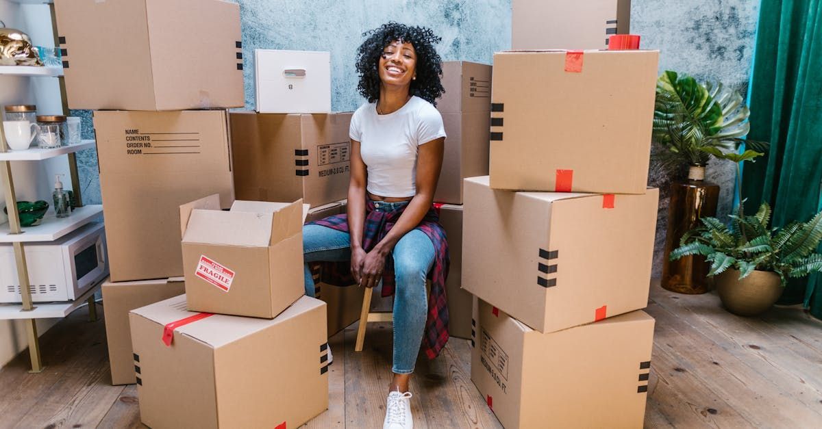 A woman is sitting in front of a pile of cardboard boxes.