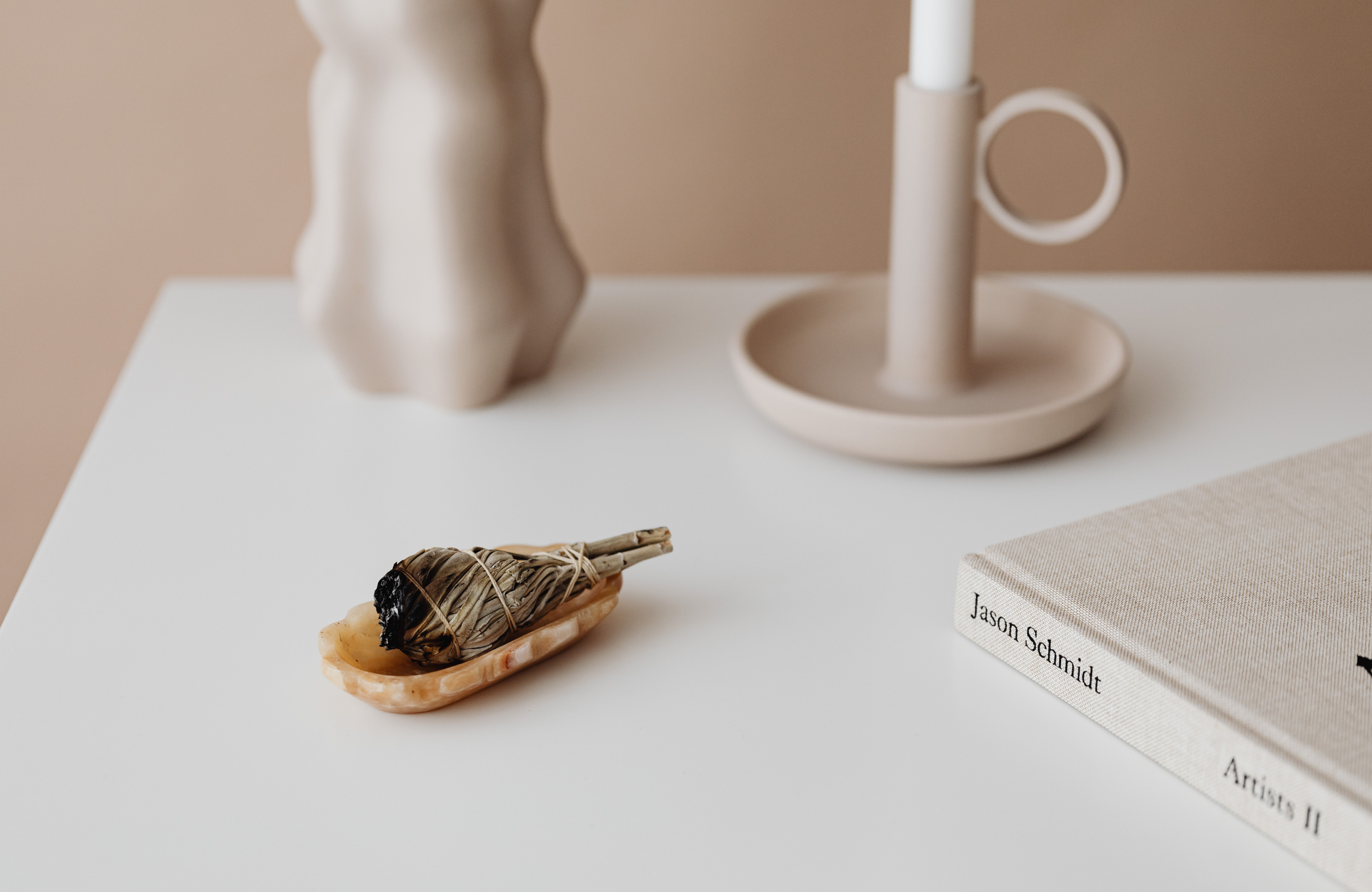 Small bird figurine on a white desk beside a lamp and an open book