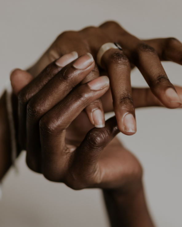 Two hands gently touching, with soft natural light on a neutral background.