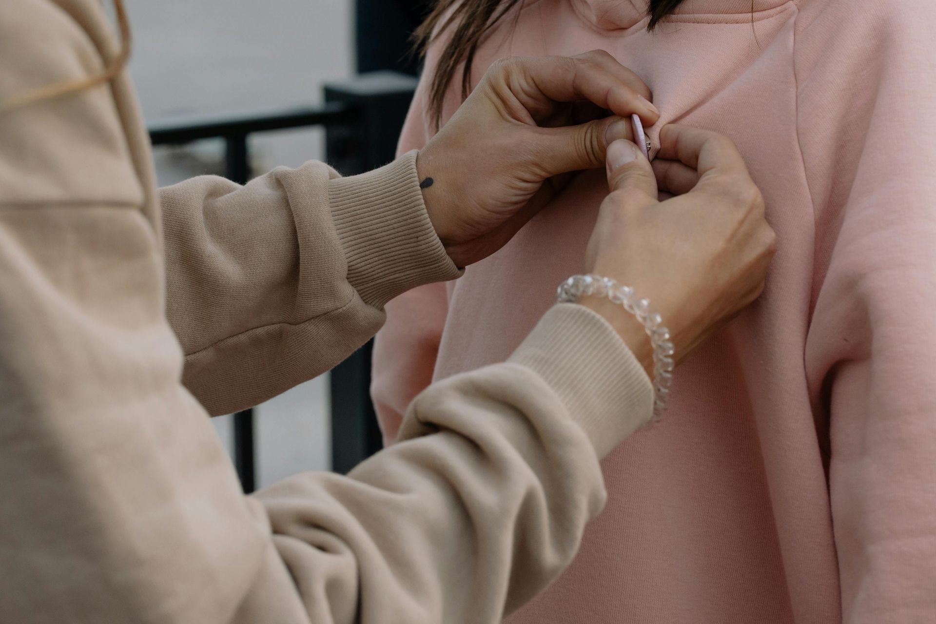 Hands fastening a small pin on a pink sweater in a close-up shot