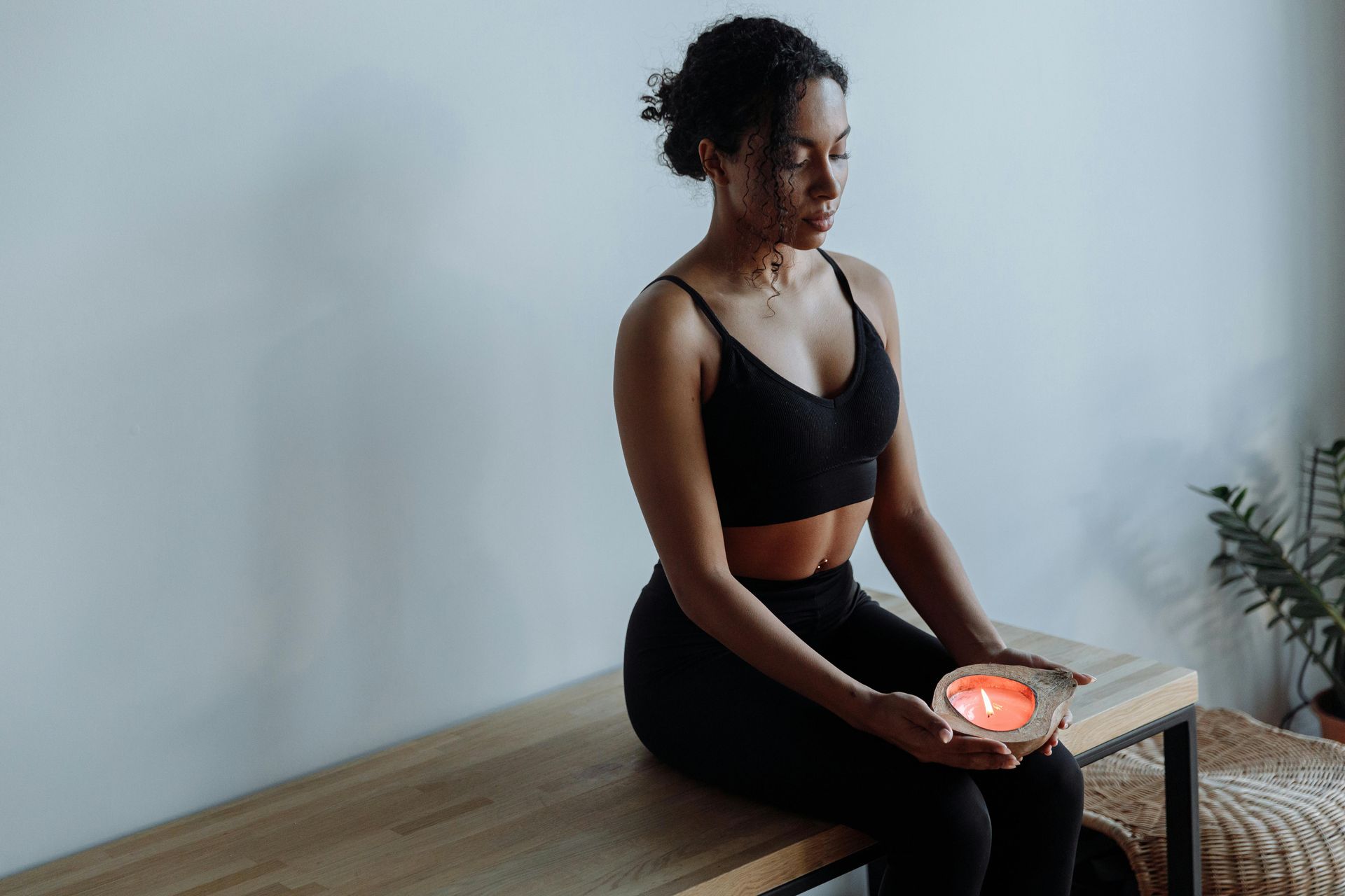Woman sitting on a bench holding a glowing bowl in a calm indoor meditation setting