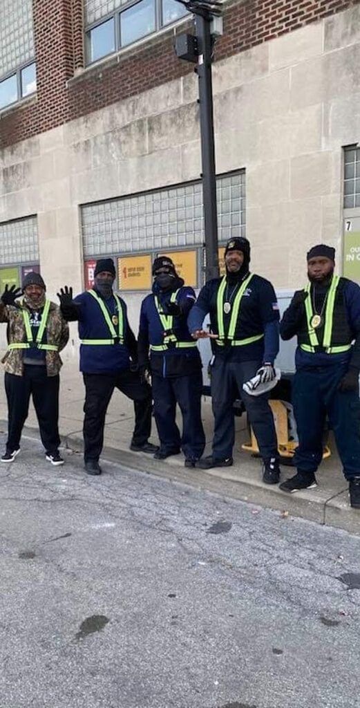 Five men in safety vests standing on a city street.