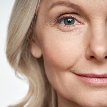 Close-up of a smiling face with light skin, blue eye, and short blonde hair