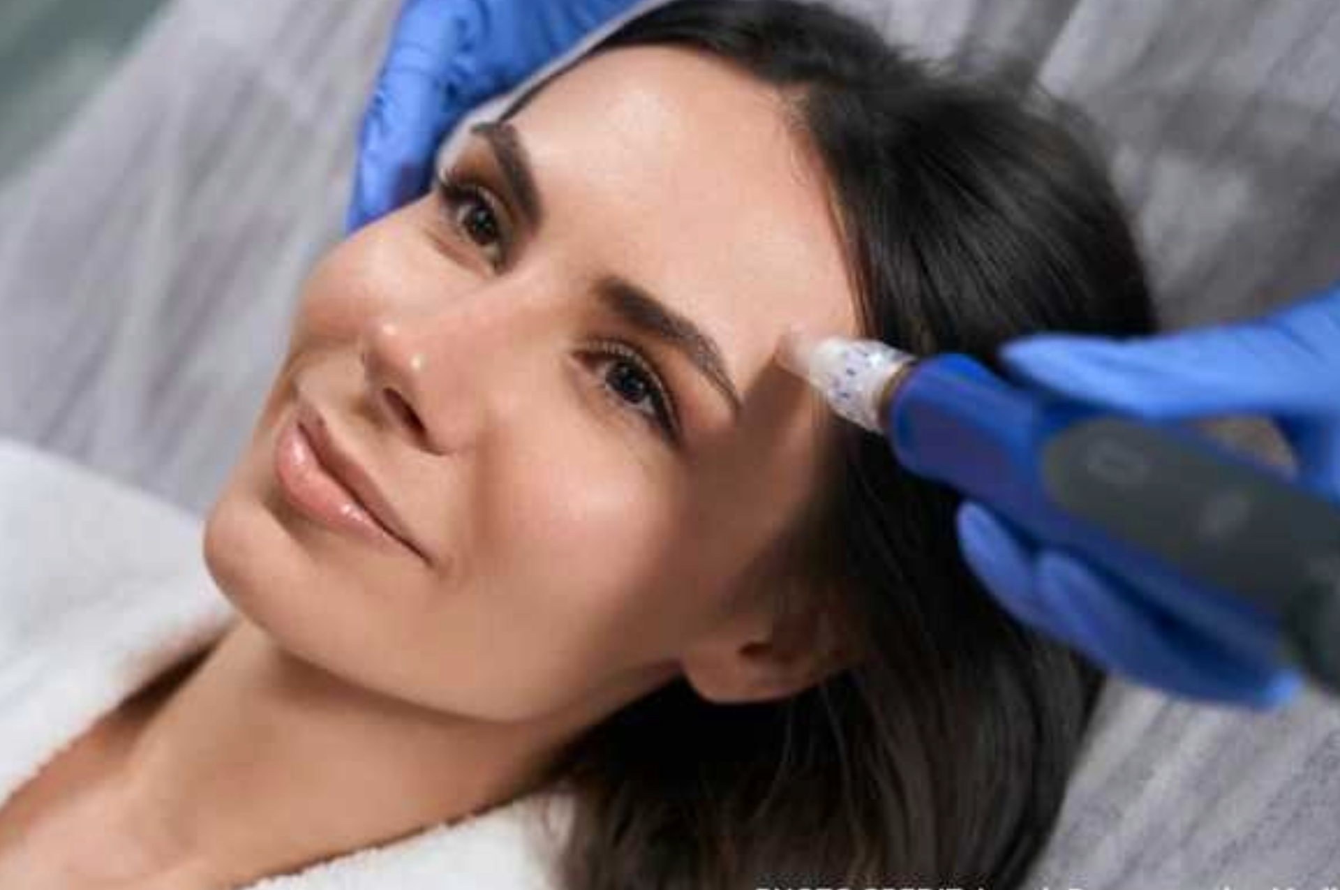 Cosmetic treatment on a woman’s forehead with a handheld device in a clinic