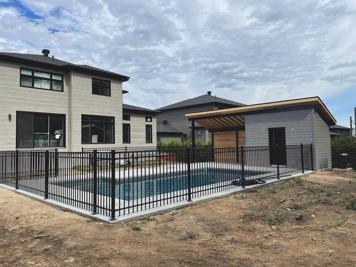 une grande piscine est entourée d une clôture métallique dans la cour d une maison.
