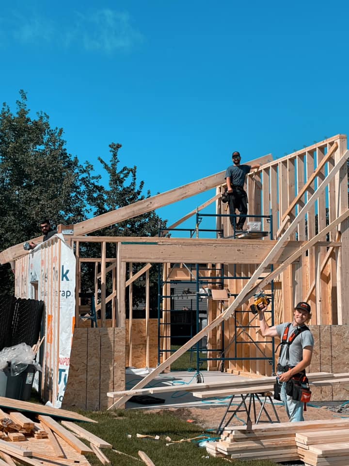 Des ouvriers du bâtiment construisent la charpente d'une maison par une journée ensoleillée.