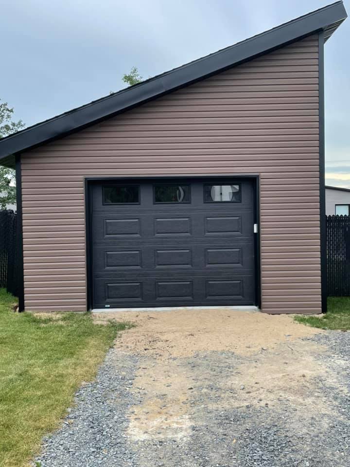 un garage avec un toit en pente et une porte de garage noire.
