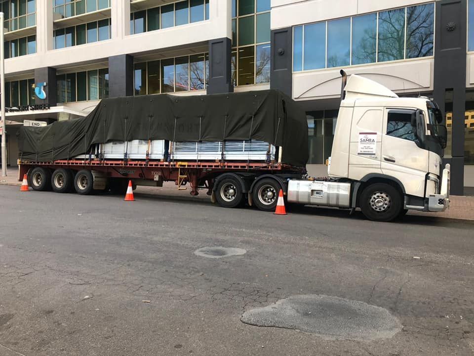 A semi truck is parked on the side of the road in front of a building.