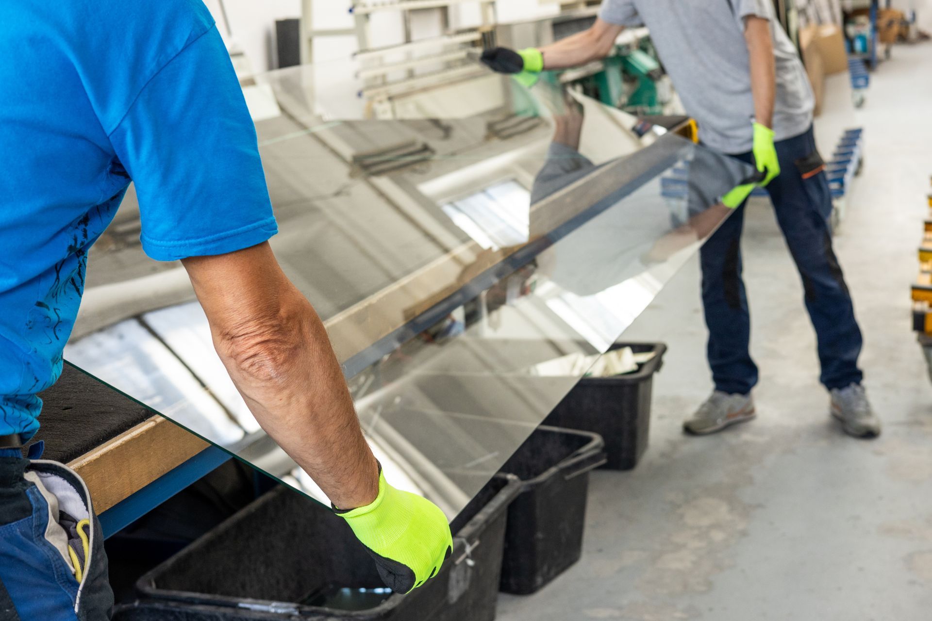 Workers handling large glass panel during glass replacement at manufacturing facility Workers handling large glass panel during glass replacement at manufacturing facility