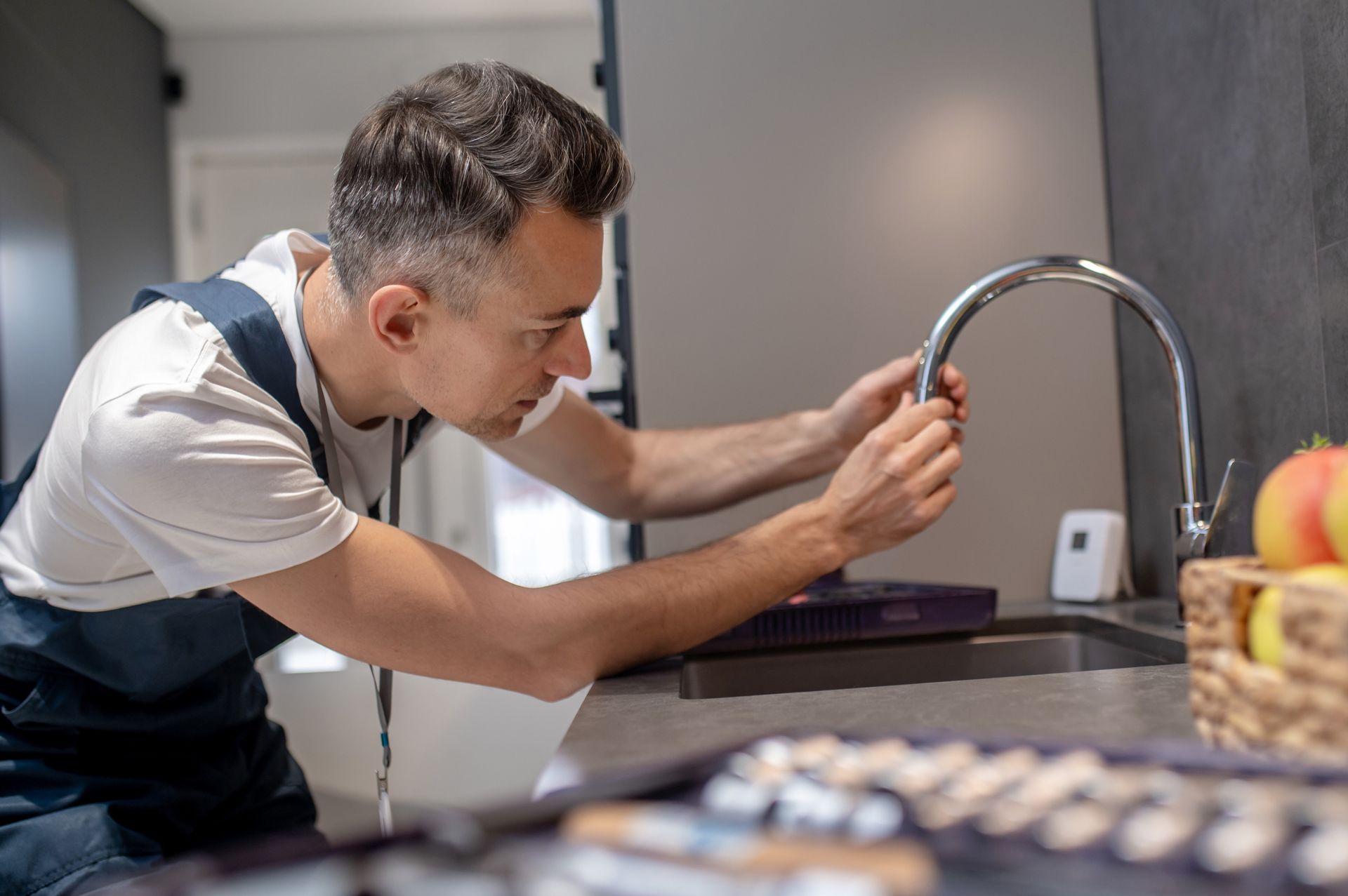 Person tightening a faucet in a modern kitchen sink