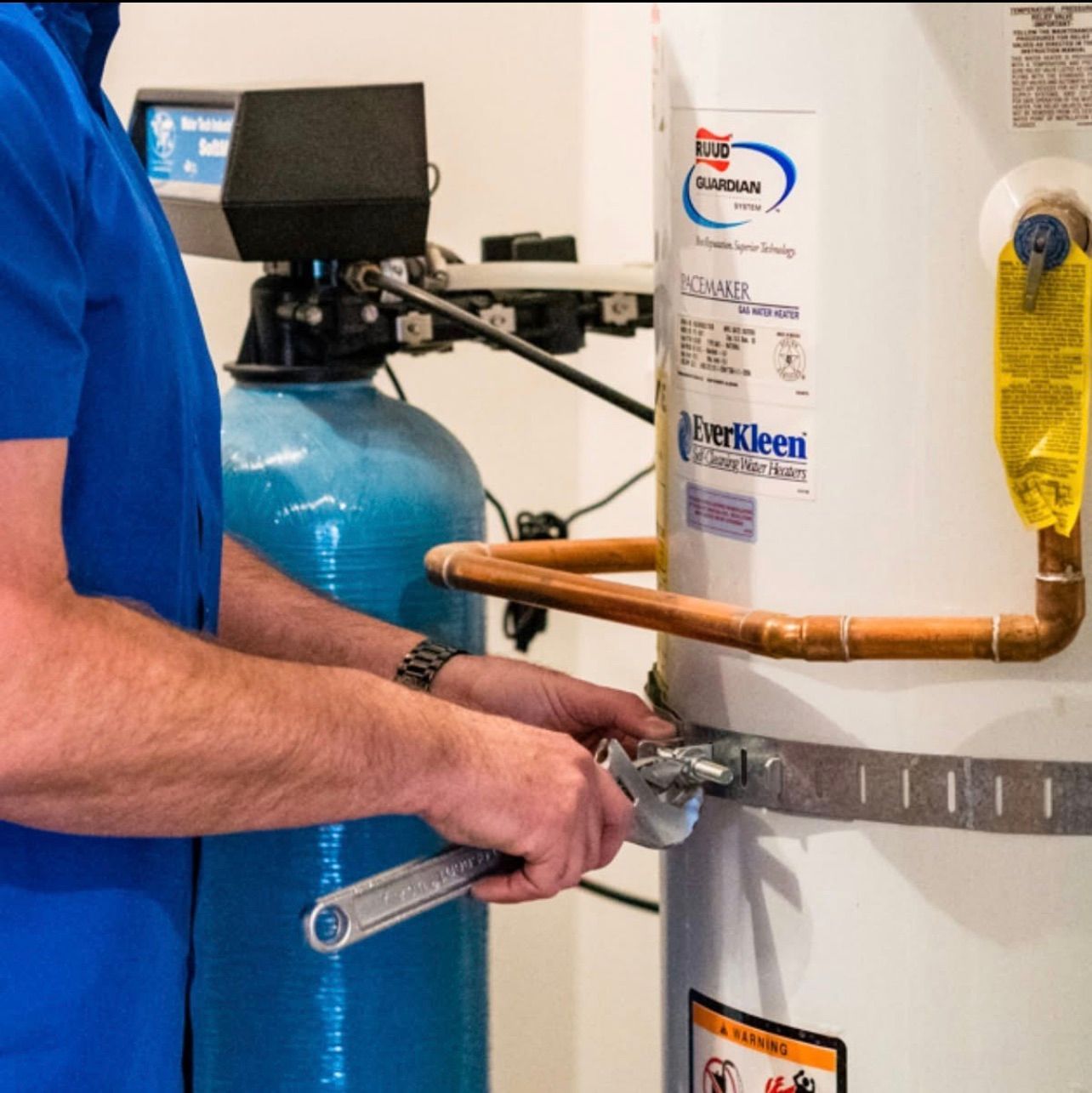 A man in a blue shirt is working on a water heater
