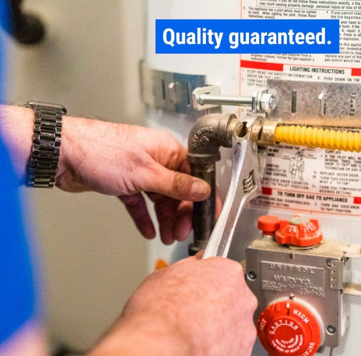 A person is working on a water heater with a sign that says quality guaranteed
