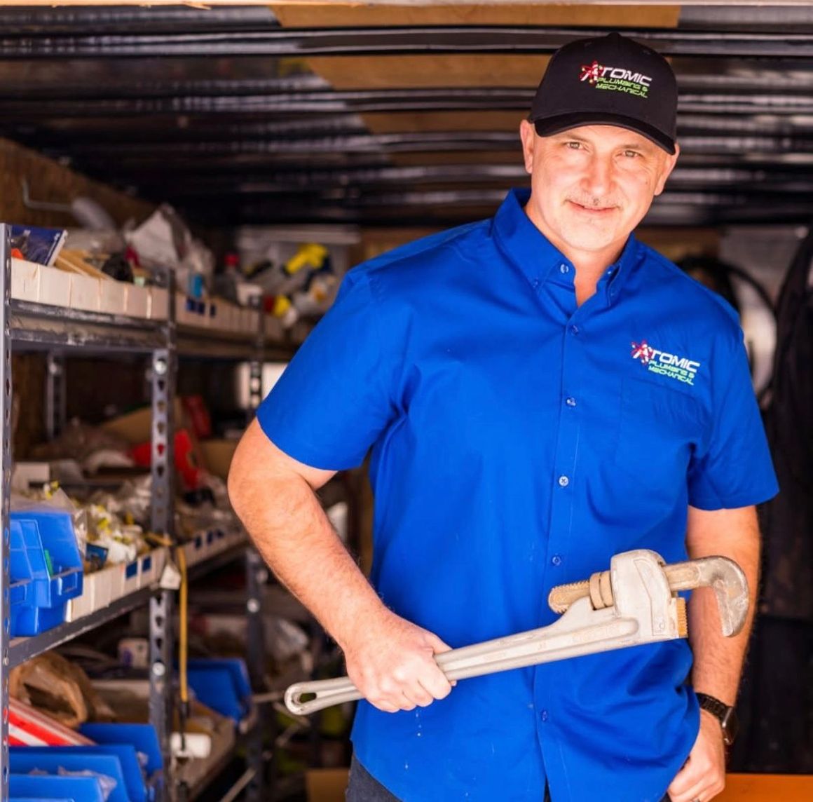 A man in a blue shirt is holding a wrench