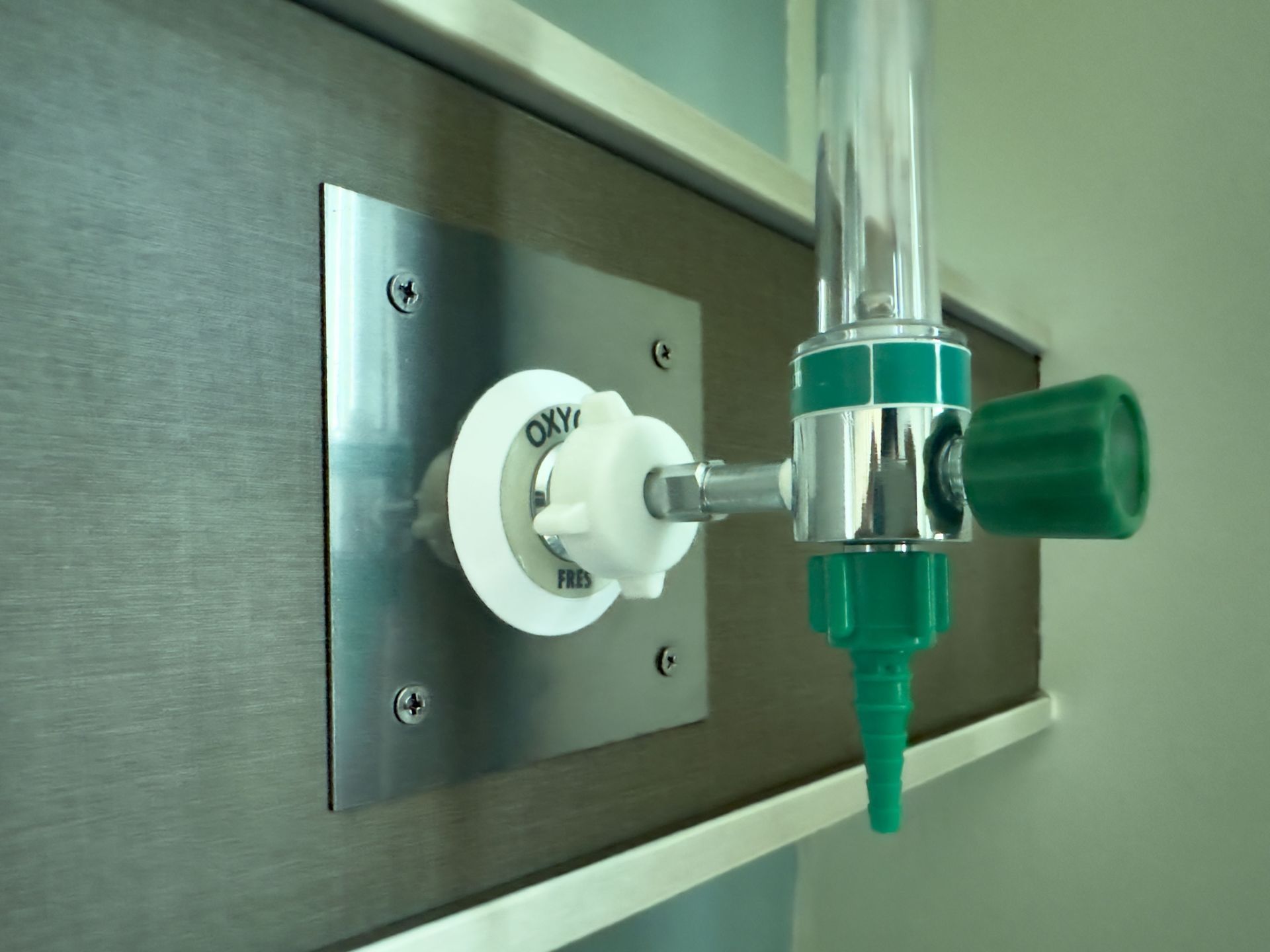 A green and white oxygen valve is attached to a wall