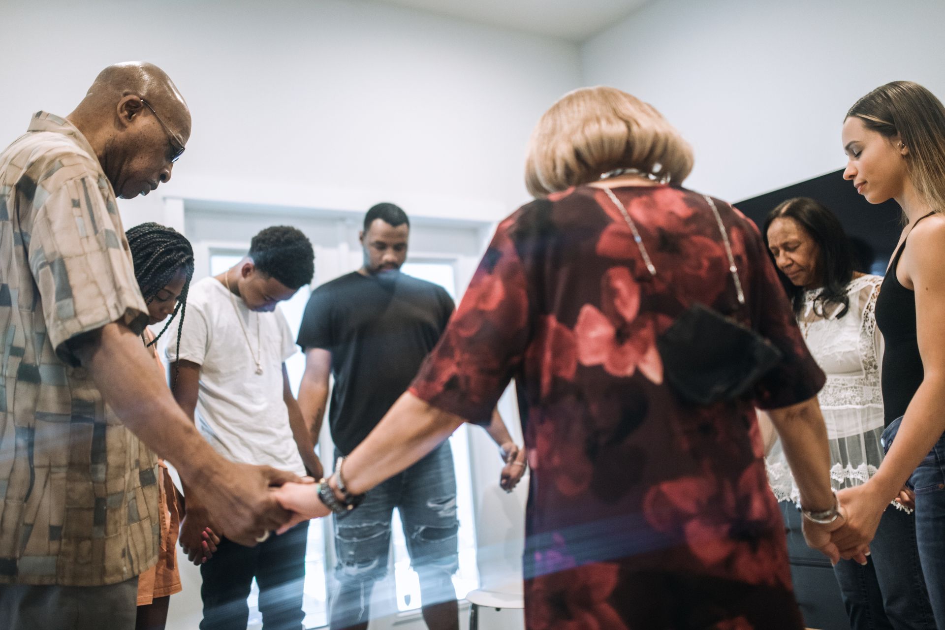 A group of people are holding hands in a circle in a room. A group of people are holding hands in a circle in a room.