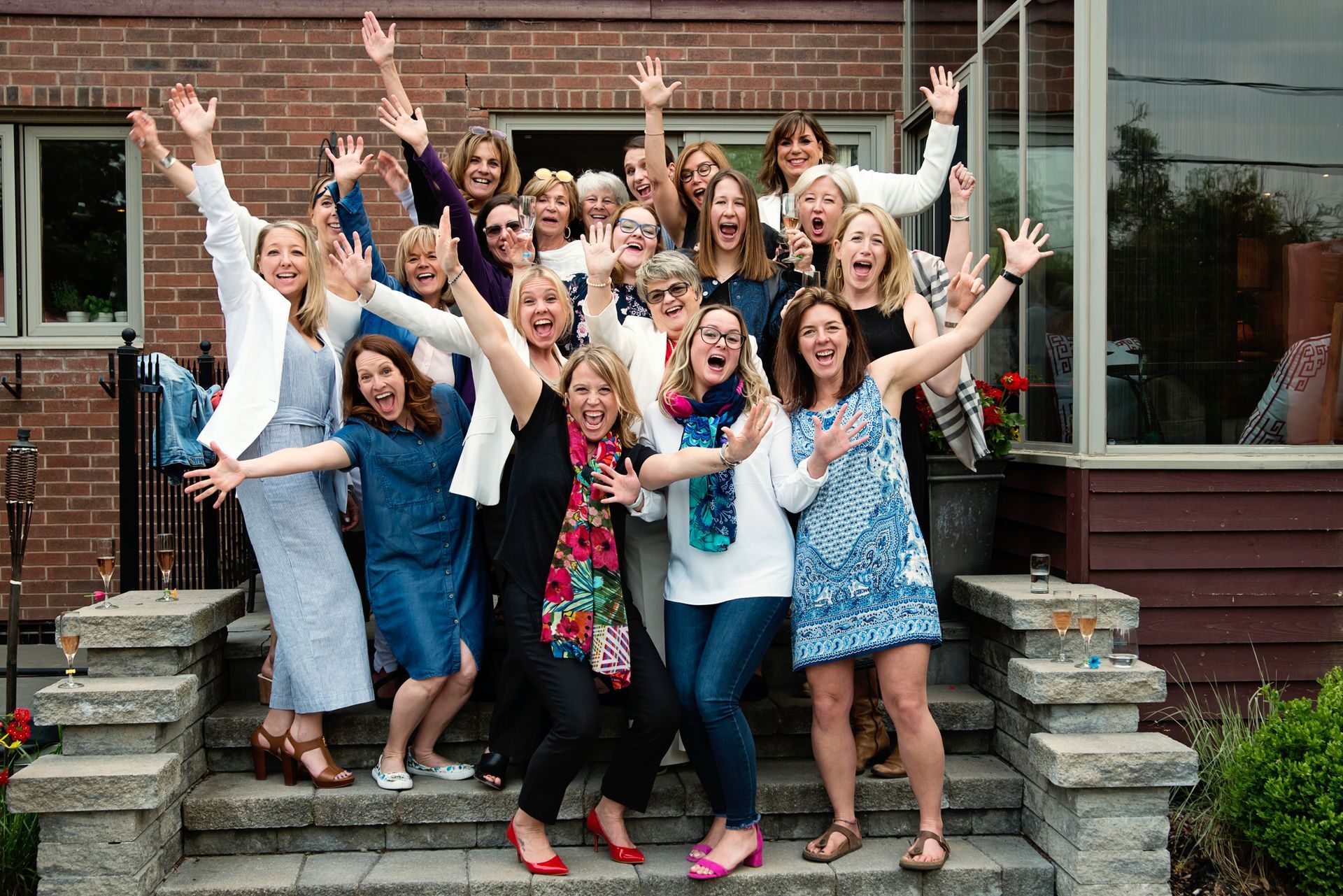 A group of women are posing for a picture on the steps of a house. A group of women are posing for a picture on the steps of a house.