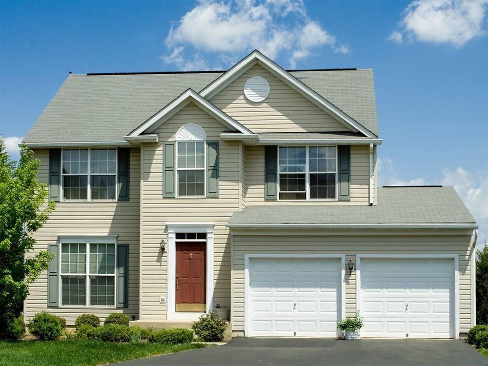 A house with two garage doors and a red door