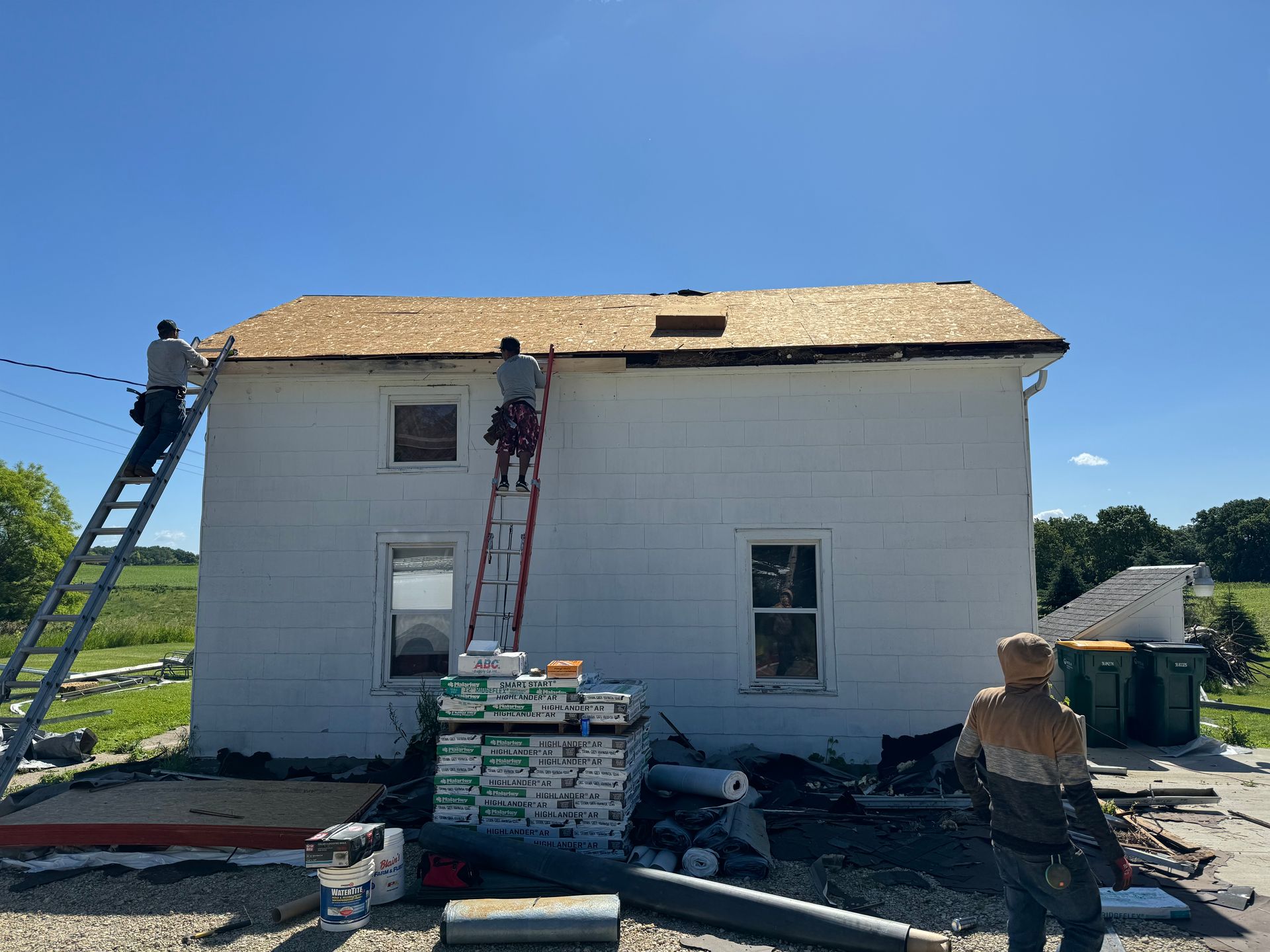 Two men are working on the roof of a white house.