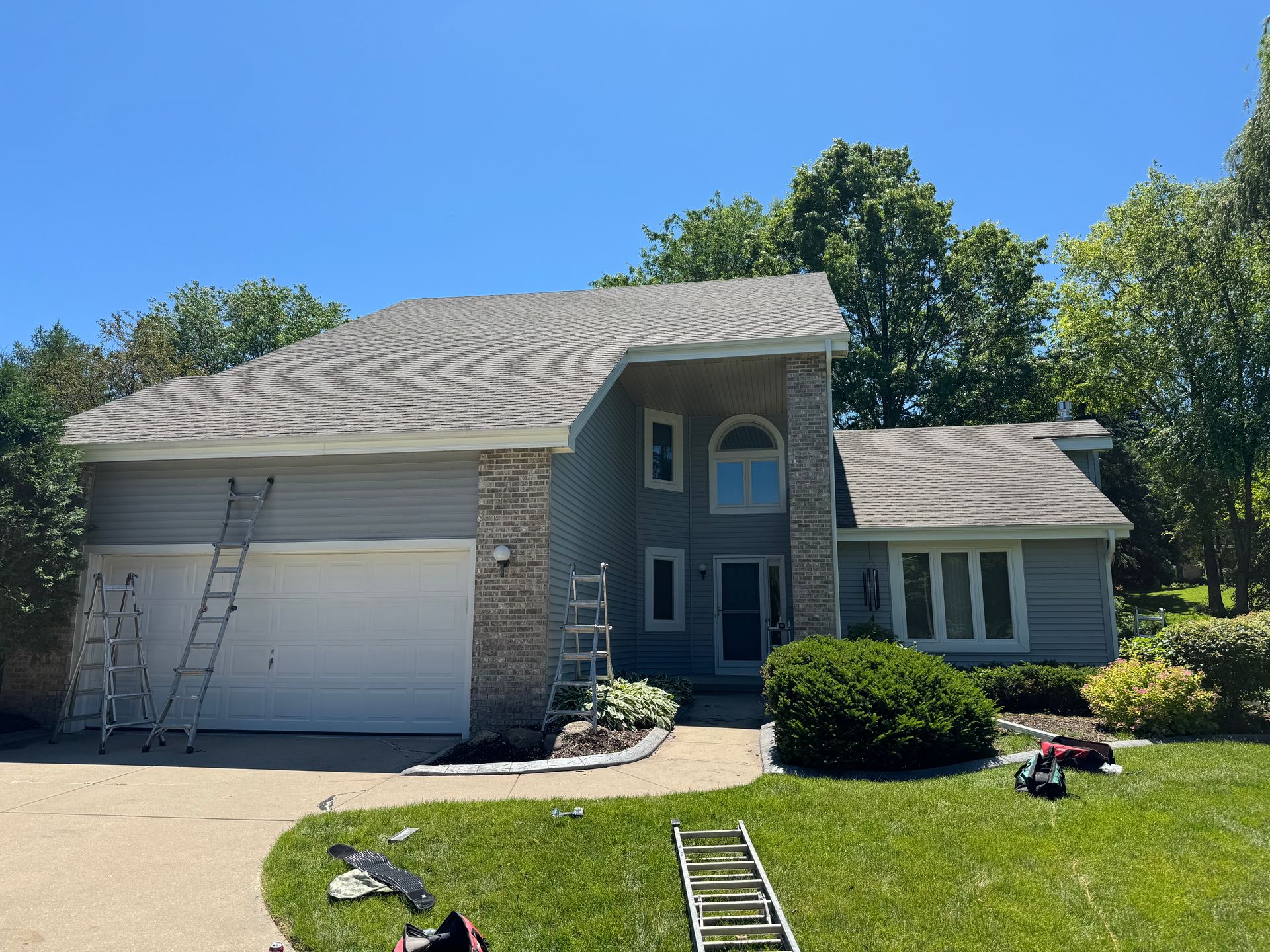 Custom-bent fascia and gutter installation underway on a Janesville, WI home with ladders and materials on site.