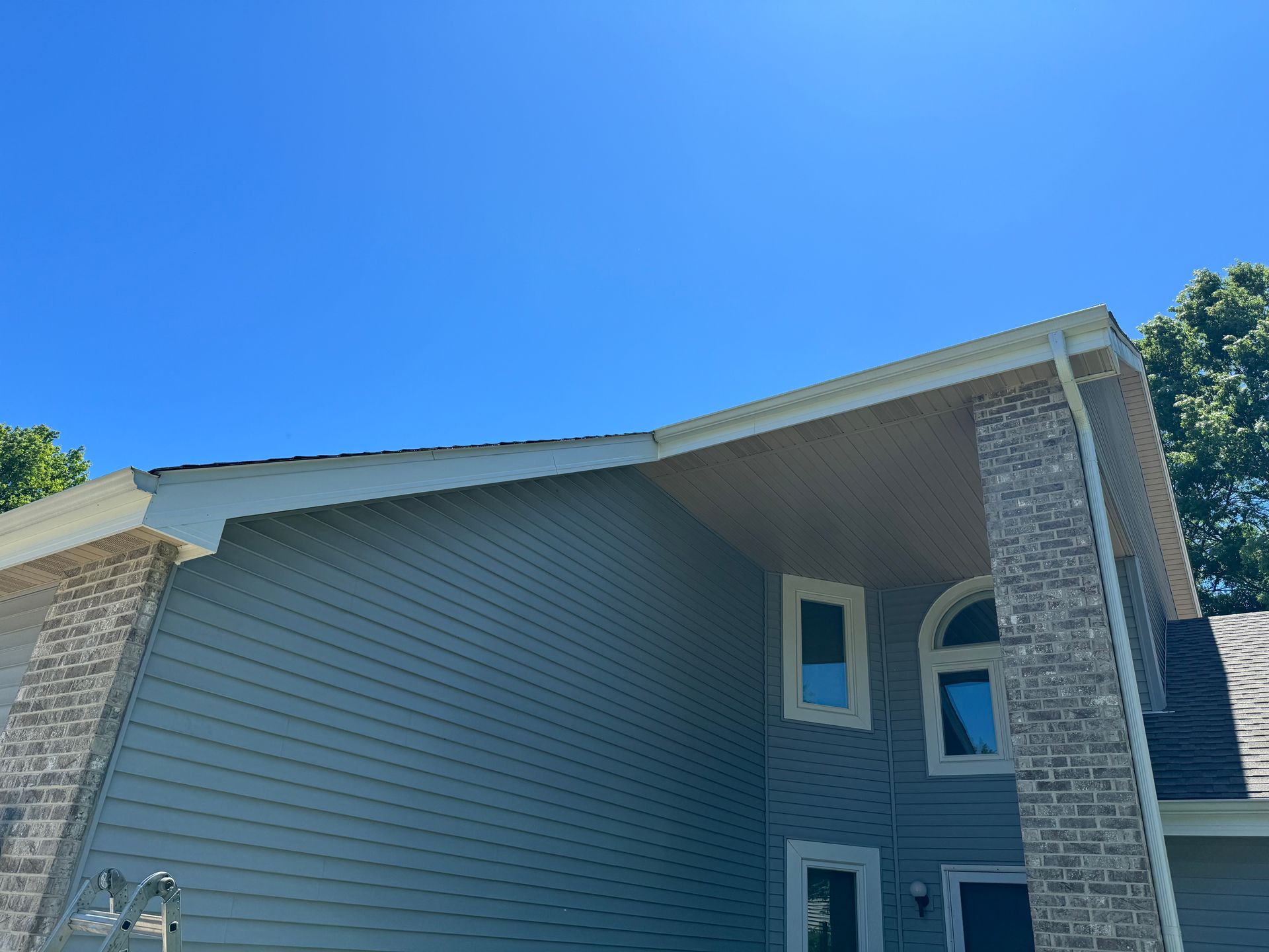 Completed custom-bent fascia installation on a gray Janesville home with clean white roofline trim.